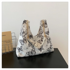 Gros plan du motif papillon noir sur le sac cabas en toile blanche texturée