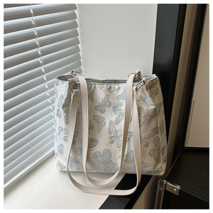 Detail view of blue and gold butterfly jacquard texture on white tote bag with leather strap