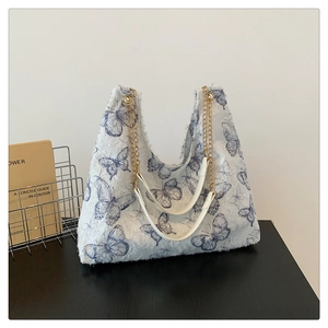Gros plan du sac cabas en peluche blanche avec motifs papillons bleus et chaîne dorée