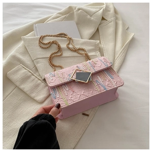 Detail der rosa bestickten Handtasche mit bunten Wellenmustern und goldener Kettenriemen