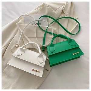 Chic mini leather handbags in white and green with gold metal logo on a magazine