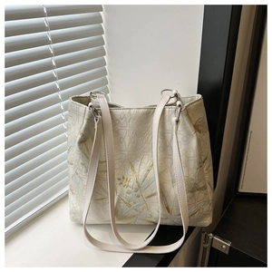 Detail of embroidered bamboo leaves on an elegant cream tote bag with soft sunlight shadows