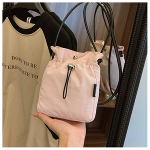 Detail of pink nylon crossbody bag with drawstring closure and fashion side label