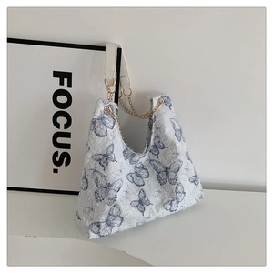Détail du sac cabas à motif papillon avec chaîne dorée et texture brodée élégante