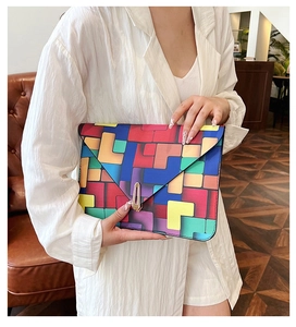 Detail of colorful geometric envelope clutch bag with golden metal buckle closure