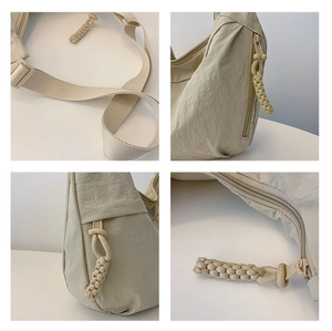 Detailed view of cream nylon dumpling bag with woven zipper pull and adjustable strap