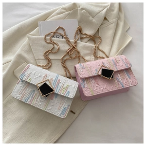 Detail der bunten Wellenstickerei auf weißen und rosa Klapptaschen mit Goldkette
