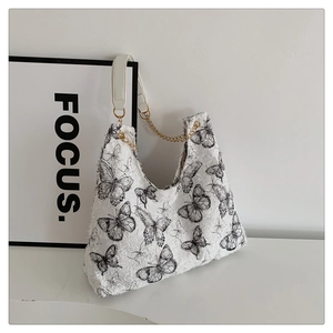 Détail du sac cabas blanc avec imprimé papillon et bandoulière en chaîne dorée