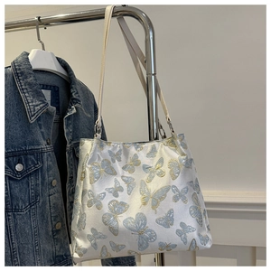 Detailed close-up of blue and gold butterfly embroidery on white satin tote bag