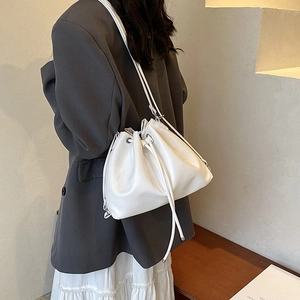 Minimalist white drawstring bucket bag with silver eyelets shown in a lifestyle crossbody style