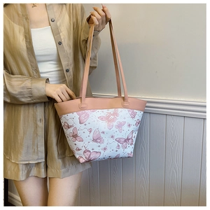 Detail of a white tote bag with purple butterfly prints and pink faux leather handles