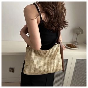 Detail of woven straw tote bag with brown leather knotted strap and natural texture