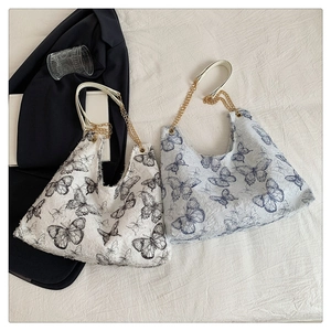 Détail de sacs fourre-tout en toile à motifs papillons et bandoulières en chaîne
