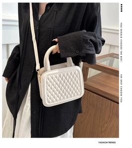 Detail of white quilted crossbody bag worn by model in a minimalist interior setting