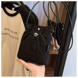 Close-up of black nylon crossbody bag with drawstring closure and silver metal hardware