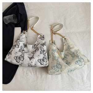Détail de cabas en toile à motif papillon avec chaîne dorée et poignée en cuir