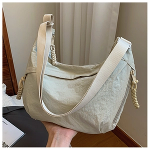 Close-up of beige nylon half-moon hobo bag with braided rope zipper detail and fabric strap