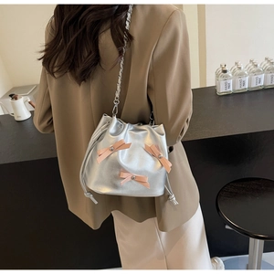 Sac seau argenté avec nœuds roses et bandoulière chaîne dans un cadre lifestyle