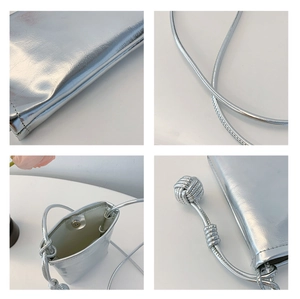 Detail of silver crossbody bag featuring magnetic closure and woven ball charm detail