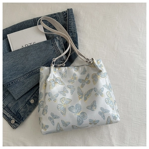 Detail of blue and gold butterfly embroidery on a soft fabric shoulder bag