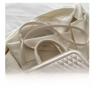 Detail view of cream quilted crossbody bag with adjustable strap and metal buckle