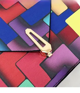 Close-up of geometric color block leather and gold hardware buckle on envelope clutch
