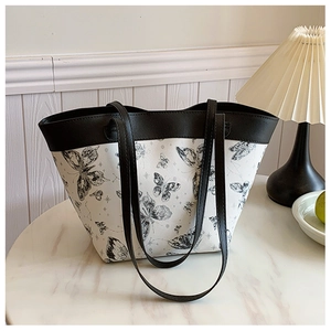 Detail view of butterfly print tote bag on marble surface with soft warm lighting