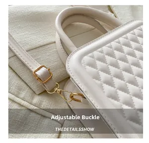 Detail of adjustable gold buckle and spring hook on cream quilted crossbody bag