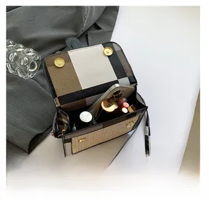 Detail showing the spacious interior of a woven crossbody bag with phone and lipstick