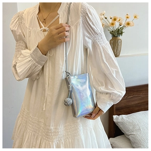 Iridescent silver crossbody phone bag with woven knot detail shown on white dress