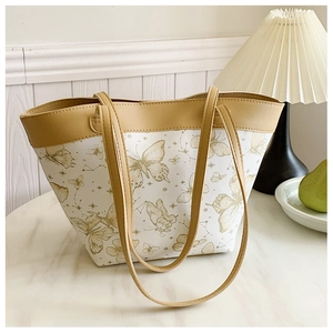 Close-up of butterfly print tote bag on marble surface with pastoral design elements
