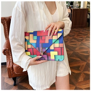 Detail of color-block geometric pattern envelope clutch with gold buckle clasp