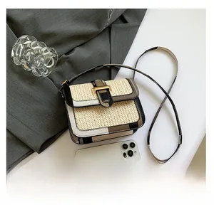 Detail of woven crossbody bag with color-block leather trim and gold metal clasp