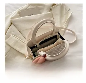 Detail view of cream leather crossbody bag interior showing daily items on beige blazer