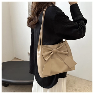 Détail d'un sac cabas beige élégant avec un grand nœud décoratif et texture en cuir PU