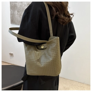 Close-up of olive green woven tote bag featuring soft leather texture and golden buckle detail