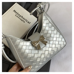 Detailed view of silver woven PU leather shoulder bag with a gold metal bow clasp