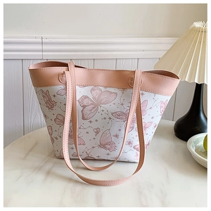 Detail of a white tote bag featuring pink butterfly patterns and matching leather straps