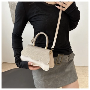 Détail du petit sac carré blanc crème avec rabat scintillant et bord inférieur ondulé