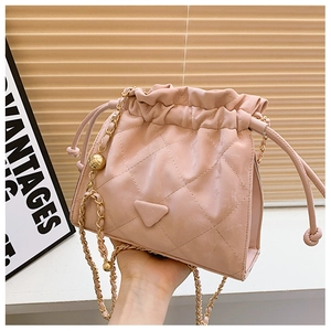 Gros plan détaillé du sac seau en cuir matelassé rose clair avec chaîne dorée