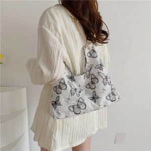 Sac fourre-tout en toile à motif papillon avec chaîne dorée porté par un mannequin