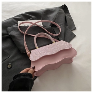 Détail du sac bandoulière rose à bords ondulés et paillettes sur un blazer gris