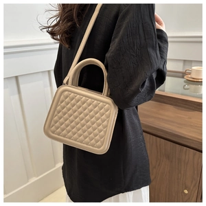 Model wearing a beige quilted crossbody bag with rhombic stitching in a home setting