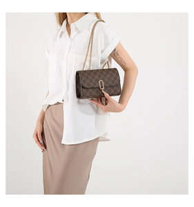 Detail view of a vintage brown monogram crossbody bag with golden chain and oval lock