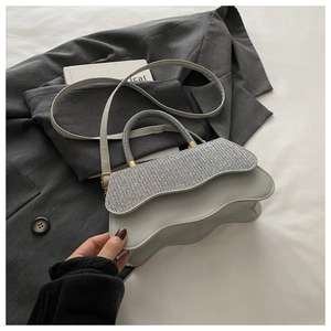 Détail du sac à bandoulière en cuir gris à bords ondulés avec strass et fermoir doré