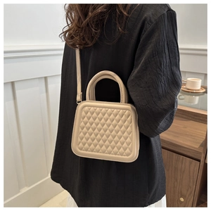 Detail of beige quilted crossbody bag shown on model in a modern lifestyle setting