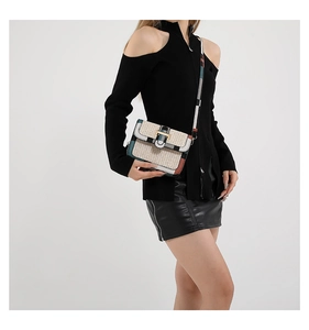 Detailed view of woven straw crossbody bag with colorful plaid edges worn by model