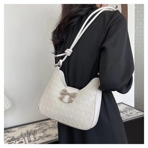 Detail of white woven hobo bag featuring silver bow clasp and knotted shoulder strap