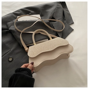 Détail du sac à rabat vague beige avec texture tissée et boucles en métal doré