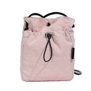 Minimalist pink nylon drawstring bucket bag with black strap on a white background